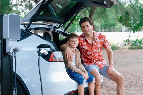 Οικογενειακές Διακοπές Ταξίδι Ηλεκτρικό Όχημα Πατέρας Και Γιος Επαναφόρτιση Αυτοκίνητο — Φωτογραφία Αρχείου