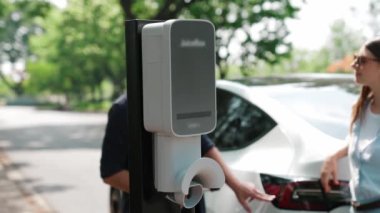 EV otomobili, tatilde milli park ve yeşillik ormanlarında çevre dostu elektrikli araçla seyahat eden çiftlerin bataryalarına elektrik yüklüyor. Yükselt