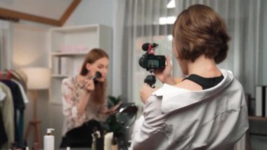 Etkilenen iki ortak canlı yayında video görüntülerini çekiyor makyaj malzemesi prim sosyal medya veya blog. Kozmetik stüdyosu ışıklandırmalı mutlu genç kız çevrimiçi pazarlama oturumu yayını için..