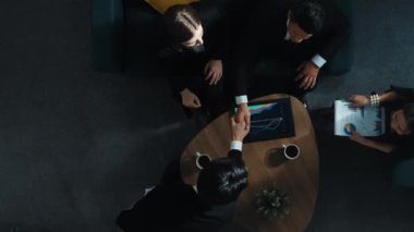 Profesyonel iş adamının yukarıdan aşağıya hava görüntüsü yatırımcıya iş belgesi dağıtırken, yönetici tablet görüntüleme istatistiklerini masaya koydu ve sunumu dinledi. Müdürlük.