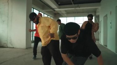 Çok kültürlü hipster grubu kameraya bakarken gökyüzü avcısıyla ya da şehir manzaralı bir binada break dans yapıyorlar. Sokak dansçısı ekibi dansçı performansına bakıyor. Açık hava sporu 2024 hiphop..