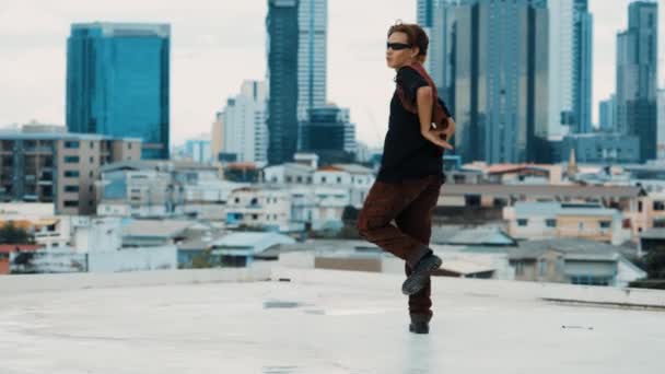 Boy舞蹈表演由专业街头舞者在屋顶上与天空碎屑 城市景观 迷人的亚洲嬉皮士表现出精力充沛的步伐 活跃的霹雳舞户外运动2024 — 图库视频影像