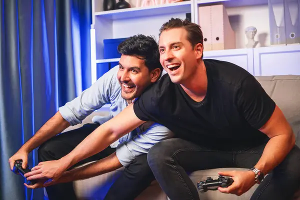 Winner and loser players of buddy friend gamers playing video game on TV using joysticks in studio room with neon blue light. Comfy living indoor at home place with cheerful fighting winner. Sellable.