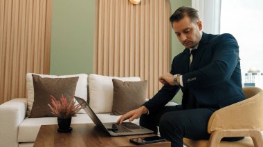 Mobilyaların üzerinde oturan işadamı hazırlanmak için süslü şirket bekleme alanında dizüstü çalışıyor. Ofis çalışanı veya iş mesleği ve ticari başarı için stratejik pazarlama planı.