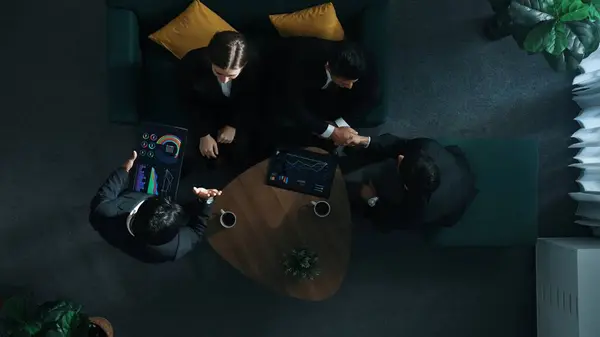 Top down aerial view of business people making agreement about collaborate business and shaking hands. Diverse group show tablet with financial statistic on table while explain plan. Directorate.