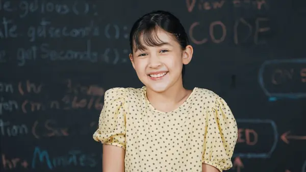 用在Stem技术课堂上编写的工程技术提示或编码 编程系统 站在黑板前对着相机笑着可爱的小女孩 聪明的学生看着相机 — 图库照片