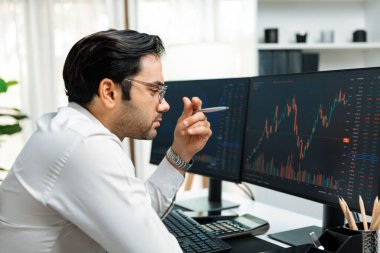 Akıllı tüccar işadamı, modern merkez ofisindeki araştırma pazarında en yüksek kârlı finansal teknolojiye yatırım yaparak bilgisayar üzerinde iki dinamik borsa yatırım ekranını analiz ediyor. Tahmin et..