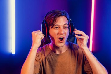 Kazanmak için çevrimiçi oyun oynayan akıllı flama makinesinin sunucu kanalı, neon ışıklı odada seçilen takım yarışması için izleyicilerle birlikte canlı yayında canlı yayında kulaklık takıyor. Bireysel.