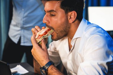 Mutlu yüzlü, sandviç yiyen ve gece iş projesinde çalışırken kahve içen iş arkadaşları. Yaratıcı serbest çalışanlar e-posta ihale kazananı online ağ uygulaması alıyorlar. Satılabilir.