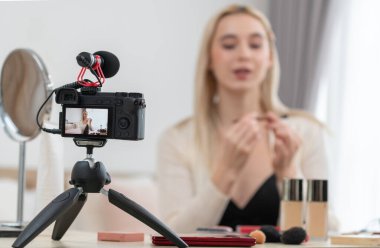 Sosyal medya için güzellik ve kozmetik video içeriği hazırlayan bulanık genç bir kadın. Güzellik etkileyicisiyle odaklanmış kamera ekranı izleyicilere ve takipçilere güzellik hizmetinin nasıl uygulanacağını gösteriyor. Blithe