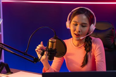 Geceleri podcast 'te olumlu konuşmalar yapan, pembe neon ışıklı modern stüdyoda sunum için dizüstü bilgisayar kullanan, gülümseyen, genç, güzel Asyalı bir etkileyiciydi. Taktik.