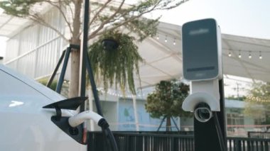Green City Park 'taki otoparkta yavaş çekim EV elektrikli araba şarj bataryası. Sürdürülebilir ve çevre dostu şehir yolculuğu için yenilenebilir otomobil için alternatif temiz enerji teknolojisi. Yararlı
