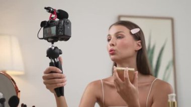 Sosyal medya için güzellik ve kozmetik video içeriği hazırlayan genç bir kadın. Güzellik blogcusu kameraya gülümserken seyircilere ve takipçilere güzellik bakımını gösteriyor. Düzenle