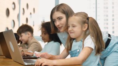 Çok kültürlü bir öğrenci dizüstü bilgisayar kullanarak mühendislik kodları yazarken öğretmen program hakkında açıklama ve öğretim yapıyor. Profesyonel eğitmen BTMM sınıfında programlama sistemini öğrenmeye yardım ediyor. Etkinlik.