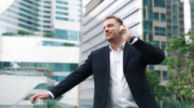 Çatıda müzik dinlerken kulaklık takan profesyonel bir işadamı. Kafkas proje yöneticisi gökdelene bakarken rahatlatıcı müziğe yöneliyor ve yeşil şehirde duruyor. Yaşam tarzı. Urbane.