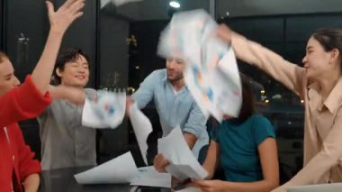 Profesyonel mutlu iş adamları başarıyı kutlamak için el çırparken evrak işlerini havaya fırlatırlar. Bir grup gülümseyen proje yöneticisi ellerini modern ofiste havaya kaldırdı. İzleme