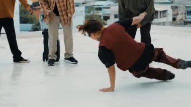 Çatıda çok kültürlü arkadaşlar varken profesyonel İspanyol break dansçısı B boy dansı. Genç modern dans grubu hip hop hareketi yapıyor. Tarz, moda, aksiyon. Açık hava sporu 2024 hiphop..