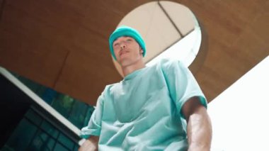 Beyaz tenli yakışıklı hippinin düşük açılı kamerası havalı poz verirken kameraya bakıyor. Arkadaşınla serbest stil dansı yaparken şık bir dansçı gülümsemesi. Açık hava sporu 2024. Sokak dansı. hiphop.
