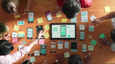 Ux ui tasarımını renkli yapışkan nota üzerine yazmak için birlikte çalışan geliştirici ekibinin üst görüşü. Tablet 'te kablo prototipi inceleyen ve yazılım tasarlayan bir grup programcı. Cemaat.