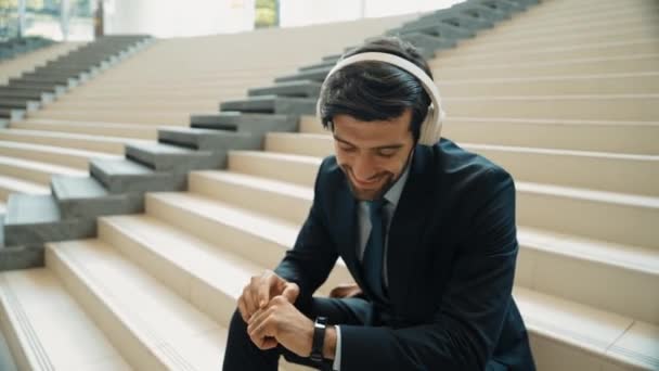 聪明的商人一边听音乐 一边戴耳机 熟练的项目经理在得到好消息的同时面带微笑 获得晋升 增加销售 放松的男人喜欢音乐 膨胀剂 — 图库视频影像