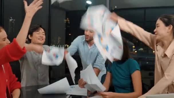 プロの幸せなビジネスマンは 成功を祝うために手をつなぎながら 紙ワークを空中に投げます 笑顔のプロジェクトマネージャーのグループは 近代的なオフィスに手を置きました トレーサリー — ストック動画