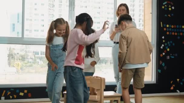 Crianças Diversas Jogando Jogos Cadeiras Musicais Enquanto Jovem Professor Bonito — Vídeo de Stock