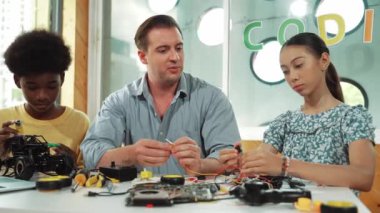 Yetenekli öğretmen Afrikalı çocuğa elektrikli aletleri açıklarken liseli kız model tamir ediyor. Çok kültürlü bir öğrenci robot araba yapımı ve elektronik aletleri öğreniyor. Öğretim
