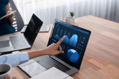 Çok ırklı analist ekibi toplantı masasındaki finansal verileri analiz etmek için BI Fintech yazılımı kullanıyor. Finansal konsol veri ekranında pazarlama göstergesi için analiz edilmiş grafikle birlikte. Uyum