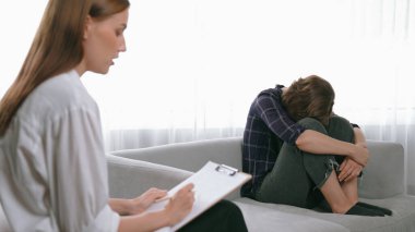 Psikologla ruh sağlığı terapisi gören üzgün travma sonrası stres bozukluğu olan bir kadın. Yaşam sonrası depresyon veya keder. Hayal kırıklığına uğramış genç bir kadın klinikteki duygular hakkında prim psikoloğuyla konuşuyor.