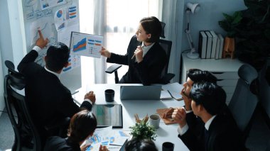 Çeşitli gruplarla pazarlama stratejisi planlarken, borsa yatırım grafiğini tutan akıllı yönetici yöneticisinin üst görüşü. Zeki iş adamları beyin fırtınası yapıyor ve birlikte çalışıyorlar. Müdürlük.