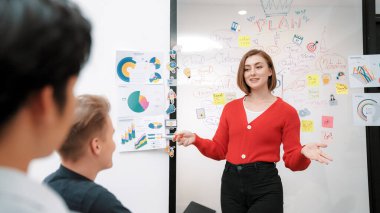 Kafkasyalı genç bir iş kadını, pazarlama stratejisini zihin haritası kullanarak sunuyor, soruları kendinden emin bir şekilde cevaplarken grafiğini çiziyor. Takım çalışması, beyin fırtınası, tartışma konsepti. Tertemiz..