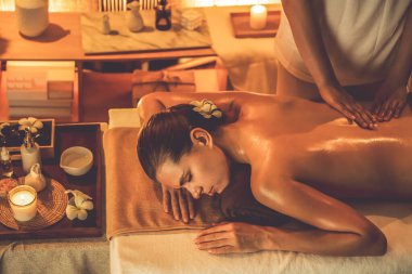 Beyaz kadın müşteri stres önleyici spa masajının keyfini çıkarıyor ve lüks otel ya da otelde sıcak mum ışığında güzellik teniyle eğleniyor. Sessiz.