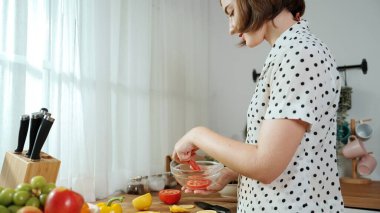 Kafkaseli anne kahvaltıda sebze pişirirken mutlu anne de modern mutfakta salata için taze malzemeler hazırlıyor. Hizmetçi sağlıklı yemek pişiriyor. Dikkat konsepti. Pedagoji.
