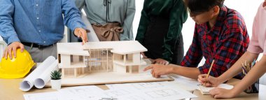 Mimari takım analizi ve ev modeli, plan ve mimari ekipmanlarla toplantı masasında ev inşaatı hakkında beyin fırtınası. Yaratıcı tasarım ve takım çalışması. Filizlenen.
