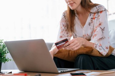 Genç mutlu kadın internetten alışveriş yaparak ürün satın alırken aynı zamanda internet üzerinden online ödeme sistemi ile çevrimiçi mağaza platformundan en yüksek siber güvenlik tarafından korunan ürünler sipariş ediyor.