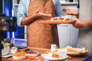 Aşçıbaşı nüfuzlu kişilerin aşçılıkta adım adım taze salata rulosu sunuşunu, sosyal medyada canlı yayında akıllı telefondan canlı yayın yapmasını, sebzeli yumuşak tortilla ambalajını göstermesini. Satılabilir.