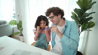 Komik beyaz bir baba ve Amerikalı bir çocuk dudak ve burun arasına kalem koyarken komik bir yüz ifadesi takınıyorlar. Birlikte mühendislik komut yazma ve masadaki dizüstü bilgisayarda yapay zeka üretme üzerine sevimli bir aile çalışması. Pedagoji.