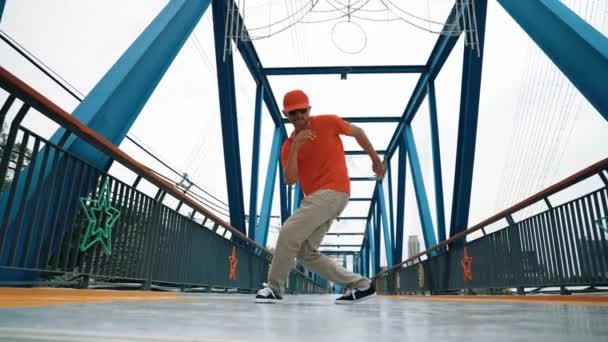 熟練したヒップスターは スタイリッシュな布を着用しながら 低角度のカメラで橋で足を踏みます プロのストレスダンサー練習ブレイクダンス 現代のライフスタイル アウトドアスポーツ 2024 スプライトリー — ストック動画