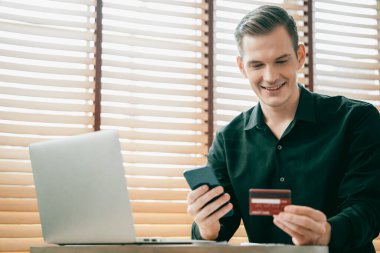 Genç adam internet bankacılığı için kredi kartlı dizüstü bilgisayar kullanıyor. İnternet üzerinden alışveriş yapıyor. Banka kartıyla modern ve kullanışlı online satın alma. Açılıyor