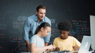 Kafkas öğretmeni elektrikli aletten bahsederken öğrenci de elektronik ekipmanlarla robot modelini tamir ediyor. Çeşitli akademik çocuklar ana kurul yapısını öğreniyor. Öğretim.