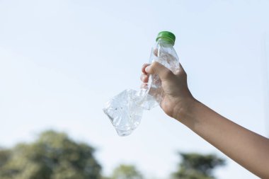 Geri dönüşümlü plastik şişe gökyüzü arka planında el ele tutulur. Geri dönüşüm için plastik atık bulundurmak etkili geri dönüşüm yönetimi ile temiz çevreyi desteklemek için konsepti azaltmak ve yeniden kullanmak. Döngü
