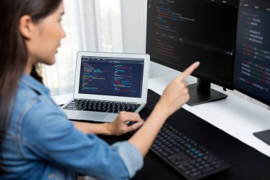 İnternet sitesinde kodlama programı uygulaması olan ve kot gömlek giyen bilgisayar hakkında bilgi veren IT geliştiricisi genç bir Asyalı kız. Güvenlik programlarıyla çevrili iki ekran. Taktik.