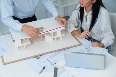 Profesyonel mühendis ev modelini tartartarken, yetenekli tasarımcı da planına yazar. Birlikte çalışmak, işbirliği, işbirliği. Yaratıcı tasarım ve takım çalışması konsepti. Üst Manzara. Tertemiz..