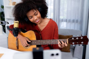 Güzel Afrikalı Kadın Etkilenen 'in sunucu kanalı akıllı telefondaki yayın stüdyosunda gitar çalarak şarkı söylüyor. Canlı sosyal medyada müzik blogcusu zamanı. Ses yaratıcısı kavramı. Tatlandırıcı.
