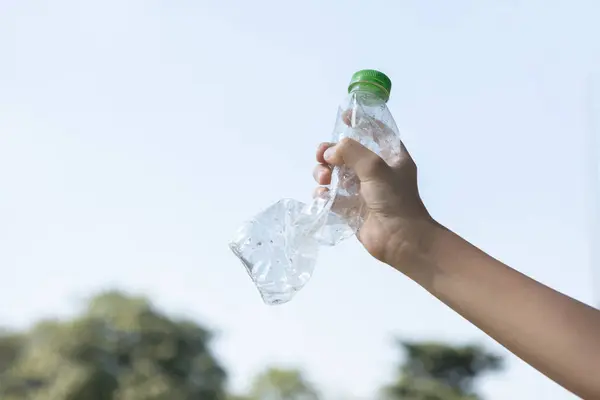 Recyclable plastic bottle held in hand up on sky background. Hand holding plastic waste for recycle reduce and reuse concept to promote clean environment with effective recycling management. Gyre