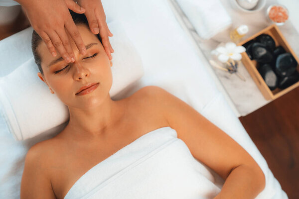 Panorama top view of woman enjoying relaxing anti-stress head massage and pampering facial beauty skin recreation leisure in dayspa modern light ambient at luxury resort or hotel spa salon. Quiescent