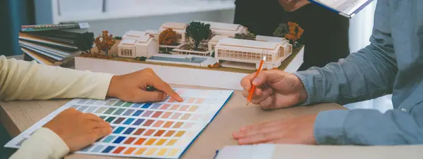 专业室内设计团队的剪裁图像讨论了项目的色彩和材料使用情况 而项目管理人员则在会议桌上选择了带有房屋模型的主题色彩 — 图库照片