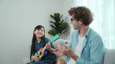 Mutlu bir babanın, ukulele çalan ve şarkı söyleyen akıllı kızına bakışının arkası. Mutlu baba motive oldu ve Amerikalı liseli kızı gitar çalmaktan zevk almaya teşvik etti. Aile eğlencesi. Pedagoji.