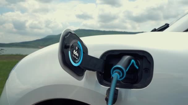 充電ステーション付き電気自動車用プラグ Ev充電ケーブルによる充電バッテリは 自然背景を持つスマートデジタルバッテリステータスホログラムを表示します 未来的なグリーンエネルギーインフラ Peruse — ストック動画