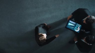 Zeki yöneticinin çeşitli takımlarla tokalaştığı ve tabletteki finansal verileri analiz ettiği yukarıdan aşağıya hava görüntüsü. Kadın lider bir anlaşma yaparak gruba katılıyor ve pazarlama stratejisini paylaşıyor. Müdürlük.